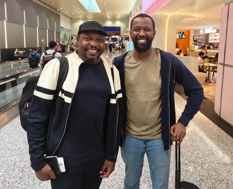 Dr. Adnan Aminu Adnan and Dr. Anas Balarabe Yazid standing together in an airport terminal, both smiling